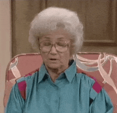 an elderly woman wearing glasses is sitting in a chair .