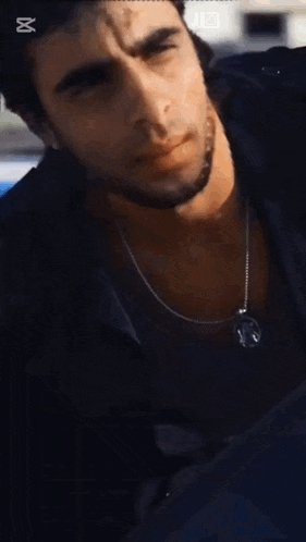 a close up of a man wearing a black shirt and a necklace with the caption capcut