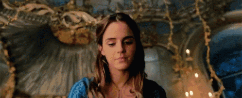 a close up of a woman in a blue dress sitting in a room with candles .
