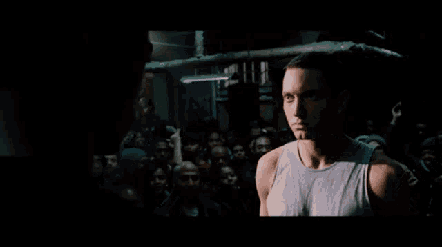 a man in a tank top is standing in front of a crowd of people