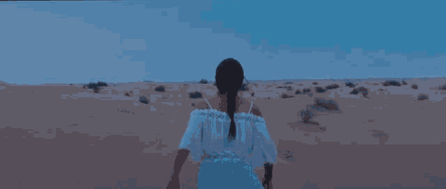 a woman in a white dress is running through the desert