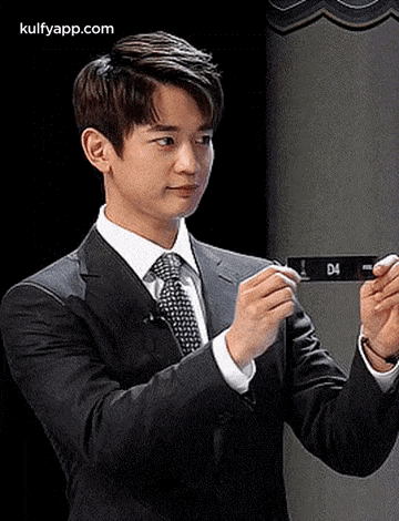 a man in a suit and tie is holding a cell phone in his hands .