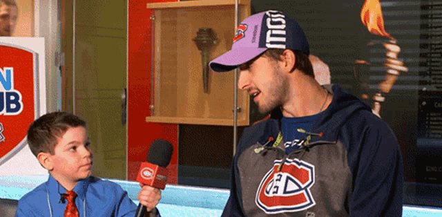 a man wearing a reebok hat is talking to a boy