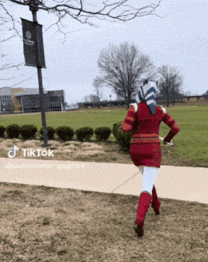 a woman in a red dress is running down a sidewalk with a sign that says tiktok