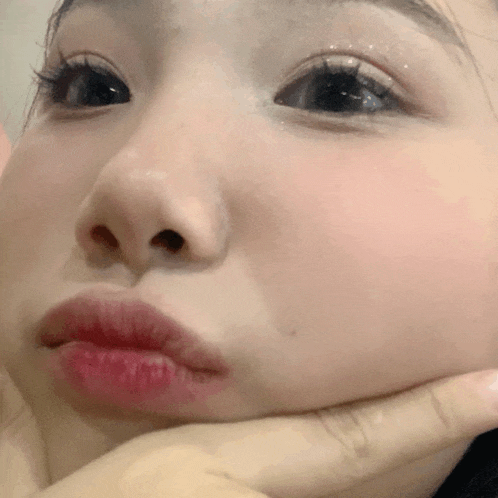 a close up of a person 's face with their hand on their chin