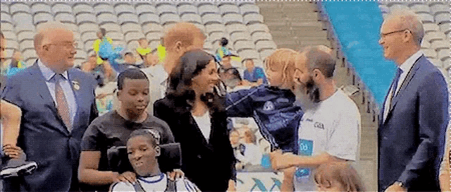 a group of people are standing in a stadium talking to each other and a woman is holding a child .
