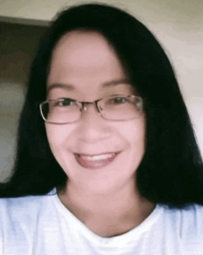 a woman wearing glasses and a white shirt is smiling