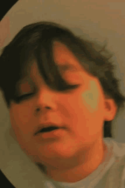 a close up of a boy 's face with his eyes closed .