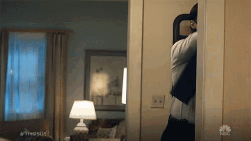 a man is standing in a doorway in a living room looking at himself in a mirror .