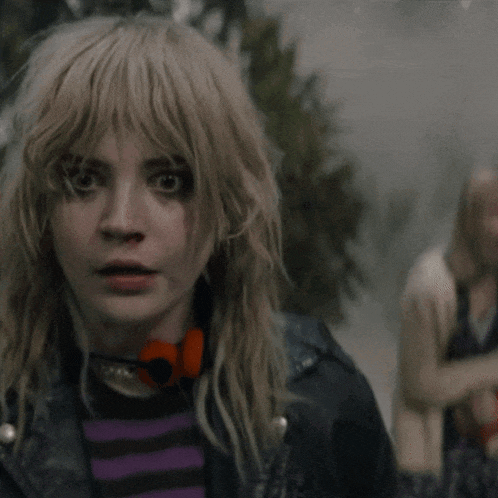 a woman with blonde hair is wearing a leather jacket and a striped shirt