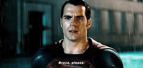 a man in a superman costume is standing in the rain and asking bruce please .