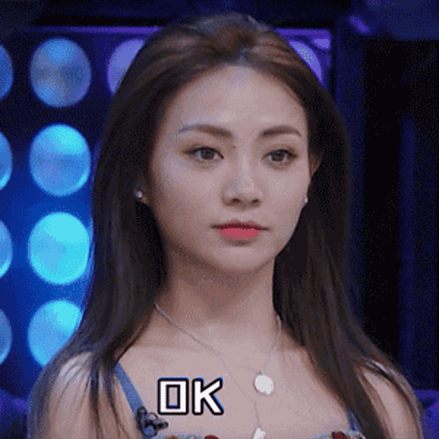 a woman with long hair is wearing a necklace with the word ok written on it