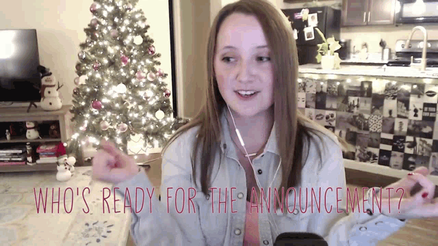 a girl in front of a christmas tree with the words who 's ready for the announcement written below her