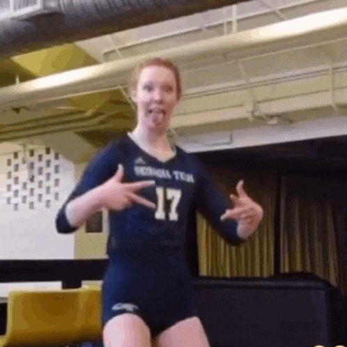 a female volleyball player wearing a number 17 jersey is dancing in a gym .