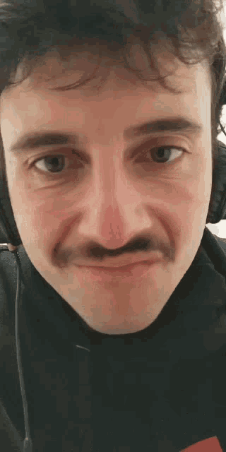a close up of a man 's face with a mustache and headphones .