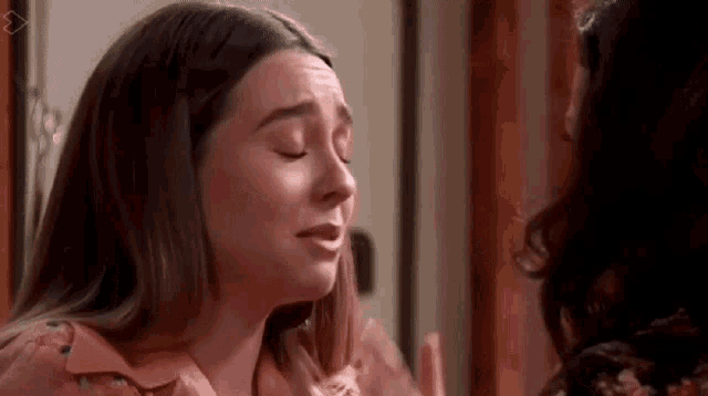 a woman is crying in front of a mirror while another woman looks at her .
