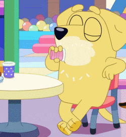 a cartoon dog is sitting at a table eating a doughnut