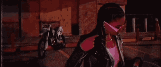 a woman wearing pink sunglasses and a leather jacket