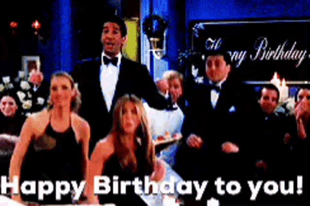 a group of people standing in front of a sign that says " happy birthday to you "