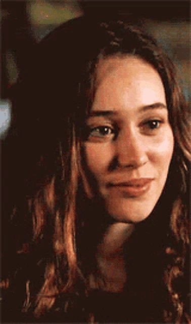 a close up of a woman 's face with long hair and a smile on her face .