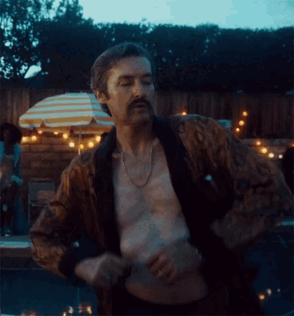 a shirtless man with a mustache is standing in front of a pool .