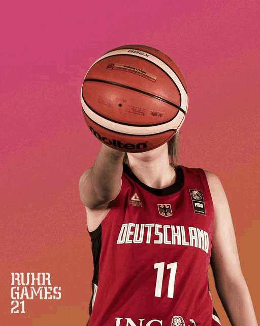 a female basketball player from deutschland is holding a molten basketball above her head
