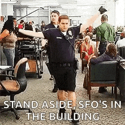 a police officer is standing in front of a crowd of people in an office .