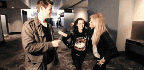 a man and two women are standing in a hallway and one of the women is wearing a virginia sweatshirt