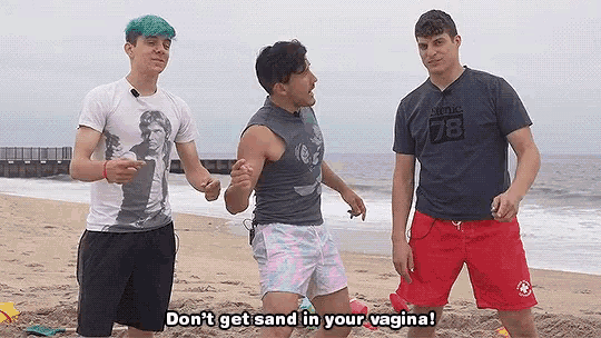 three men are standing on a beach and one of them is wearing a shirt that says 78