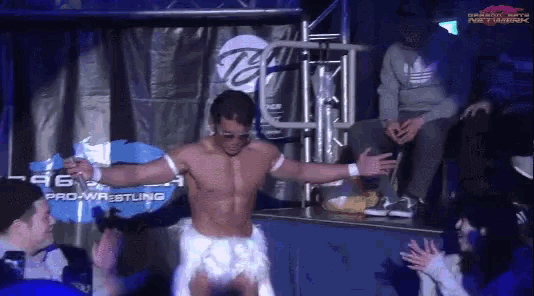 a shirtless wrestler stands in front of a banner that says pro wrestling