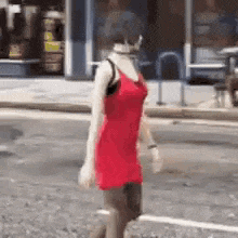 a mannequin wearing a red dress is walking down a street .