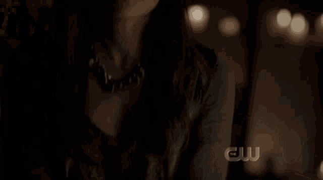a close up of a man 's face with candles in the background and a cw logo