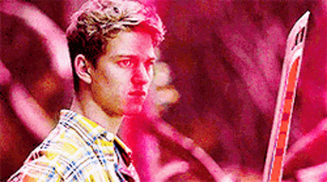a young man in a plaid shirt is holding a sword in his hand .