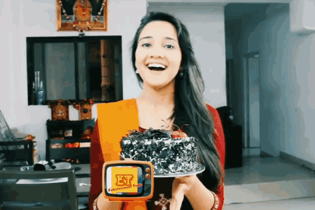 a woman is holding a cake and a tv that says ey