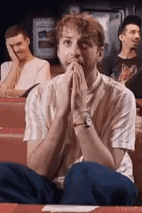 a man with his hands on his face is sitting in a row of people