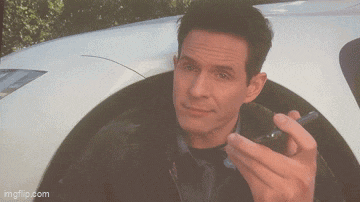 a man is smoking a cigarette in front of a car