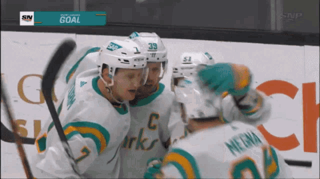 a group of hockey players are celebrating a goal with a scoreboard that says goal