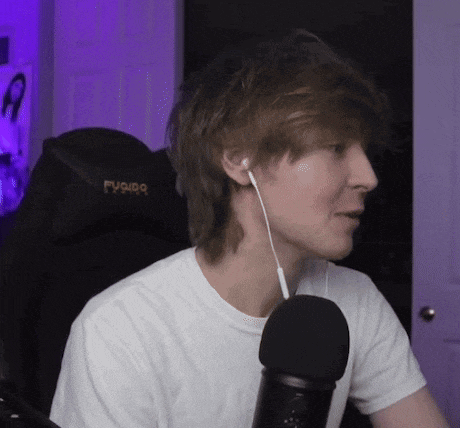 a young man wearing headphones and a white t-shirt is sitting in front of a microphone .