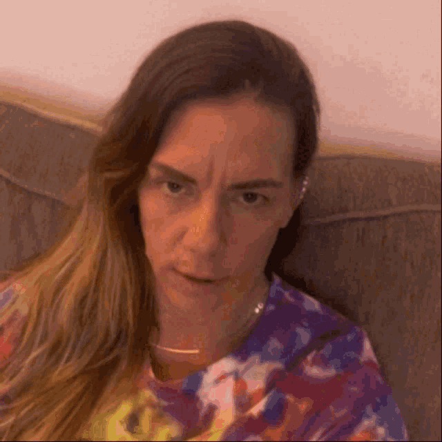 a woman is sitting on a couch and making an angry face