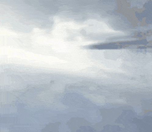a plane is flying through a cloudy sky with a yellow light in the background