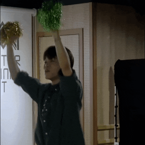 a man holds up a green pom pom in front of a sign that says n tr in t