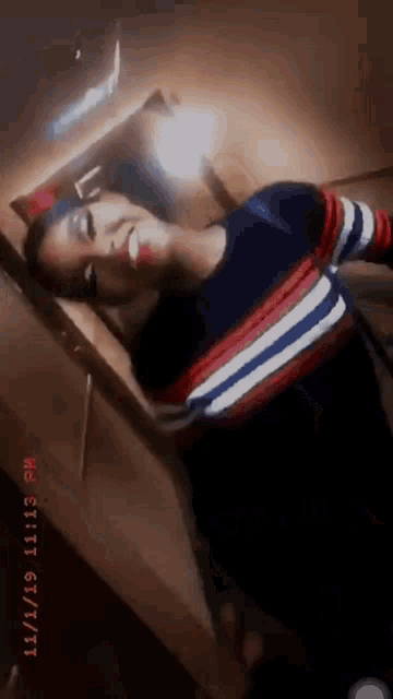 a woman is taking a selfie in a room with a striped shirt on .