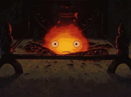 a fire with a face on it is being held by two statues