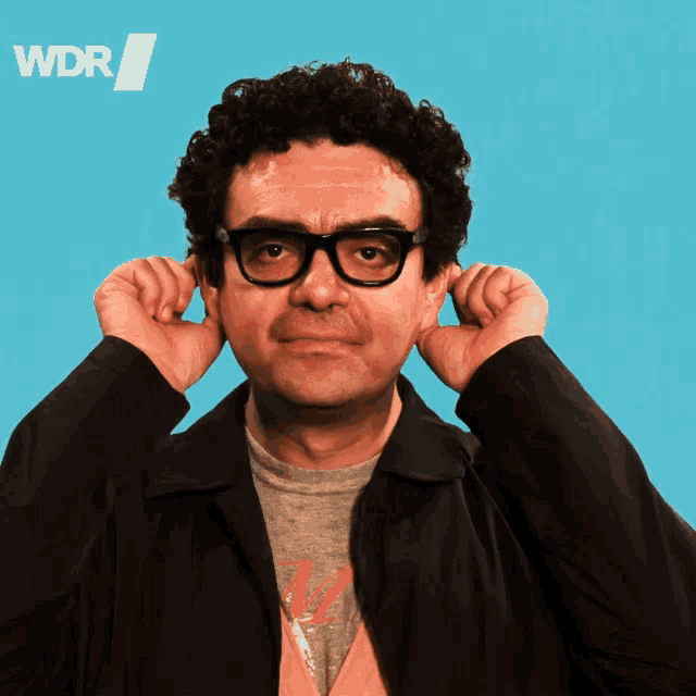 a man covering his ears in front of a blue background that says wdr