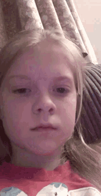 a young girl sitting on a couch with a red shirt on