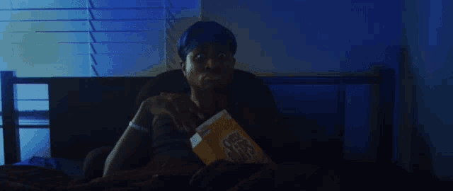 a man in a blue hat is eating a box of cheerios