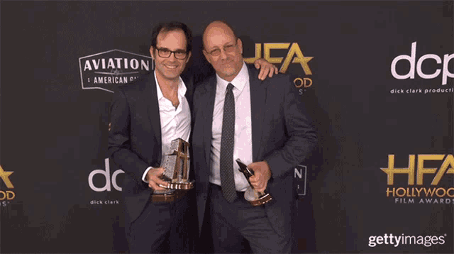 two men holding trophies in front of a sign that says aviation and american gin