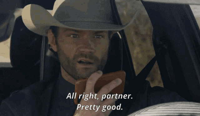 a man in a cowboy hat is talking on a cell phone and says " all right partner pretty good "