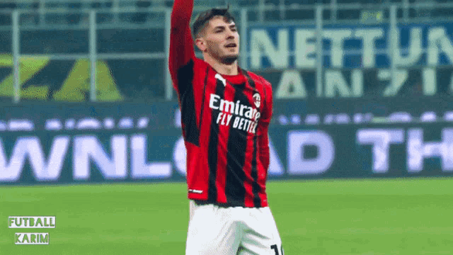 a soccer player wearing an emirates fly better jersey celebrates