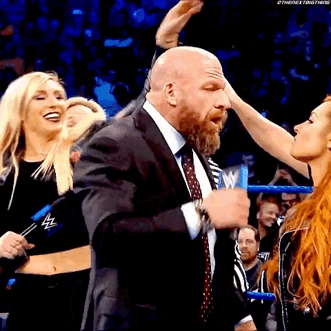 a man in a suit is being kissed by a woman in a wrestling ring .